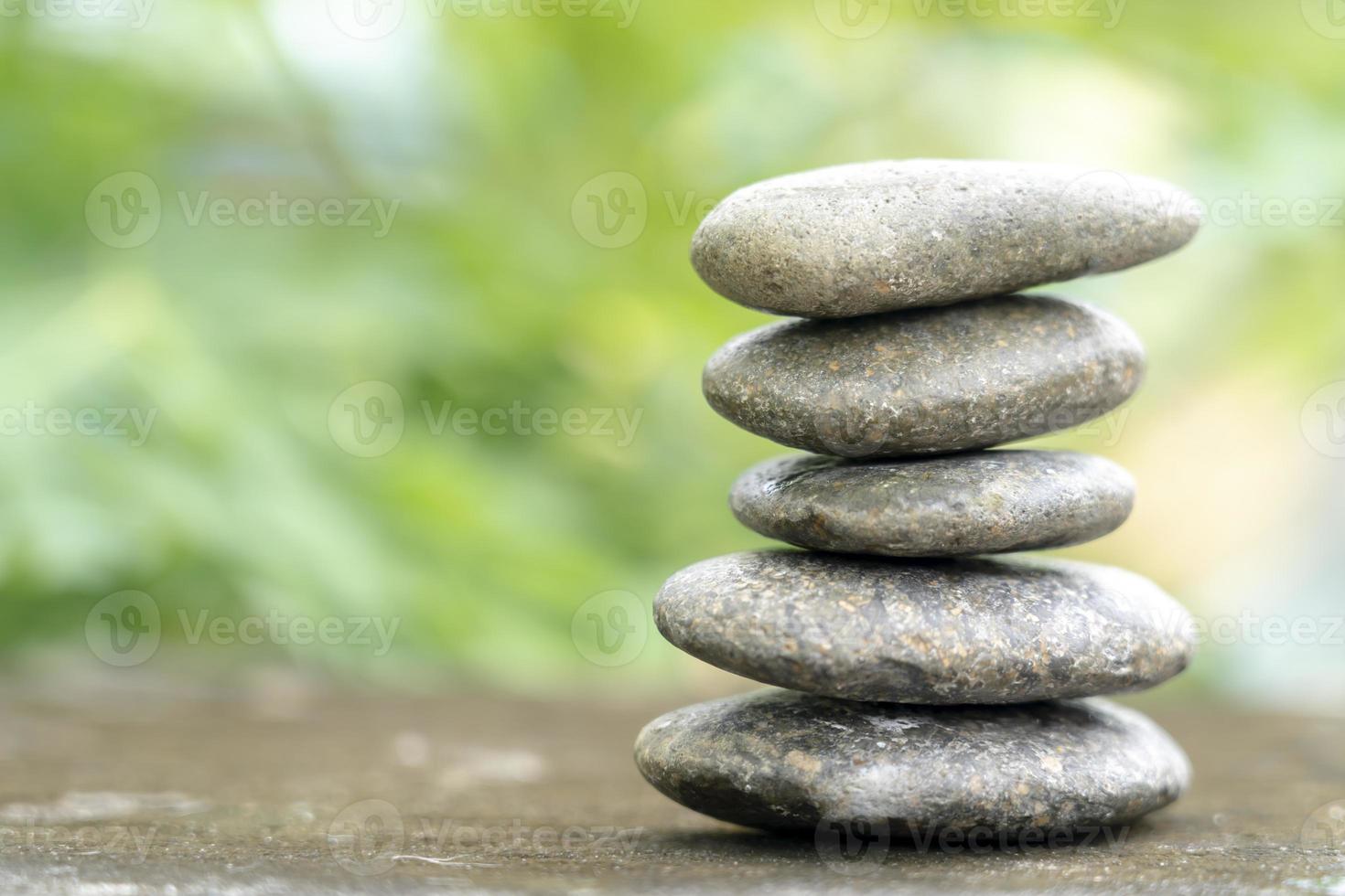 piedras de meditación con agua de gota de lluvia en el suelo de cemento sobre fondo verde de la naturaleza. espacio libre de guijarros de pirámide. calma, símbolo de budismo o concepto de conjunto de aromaterapia. foto