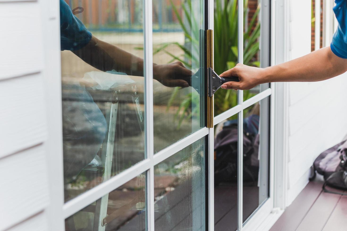 Worker use scraper cleaning window before installing tinting film. photo