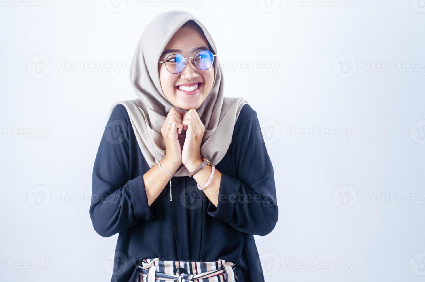 Hermosa mujer asiática sonriente se frota las manos y se ve feliz aislada sobre el fondo gris foto