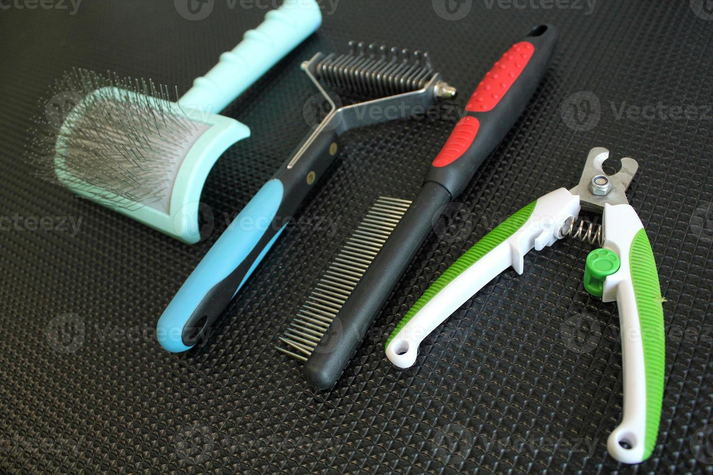 Set of professional instruments for grooming animals in salon on black table background. Clippers, brushes, combs, scissors. Pet care concept. Tools, equipment. photo