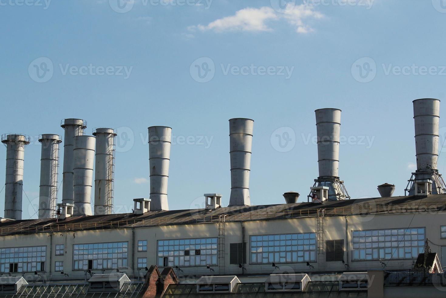Pipes of thermal power plant on a town. Industrial zone in the city. Producing electrical energy concept. Ecological and environmental issues. System of electricity supply. Saving resources efficient photo