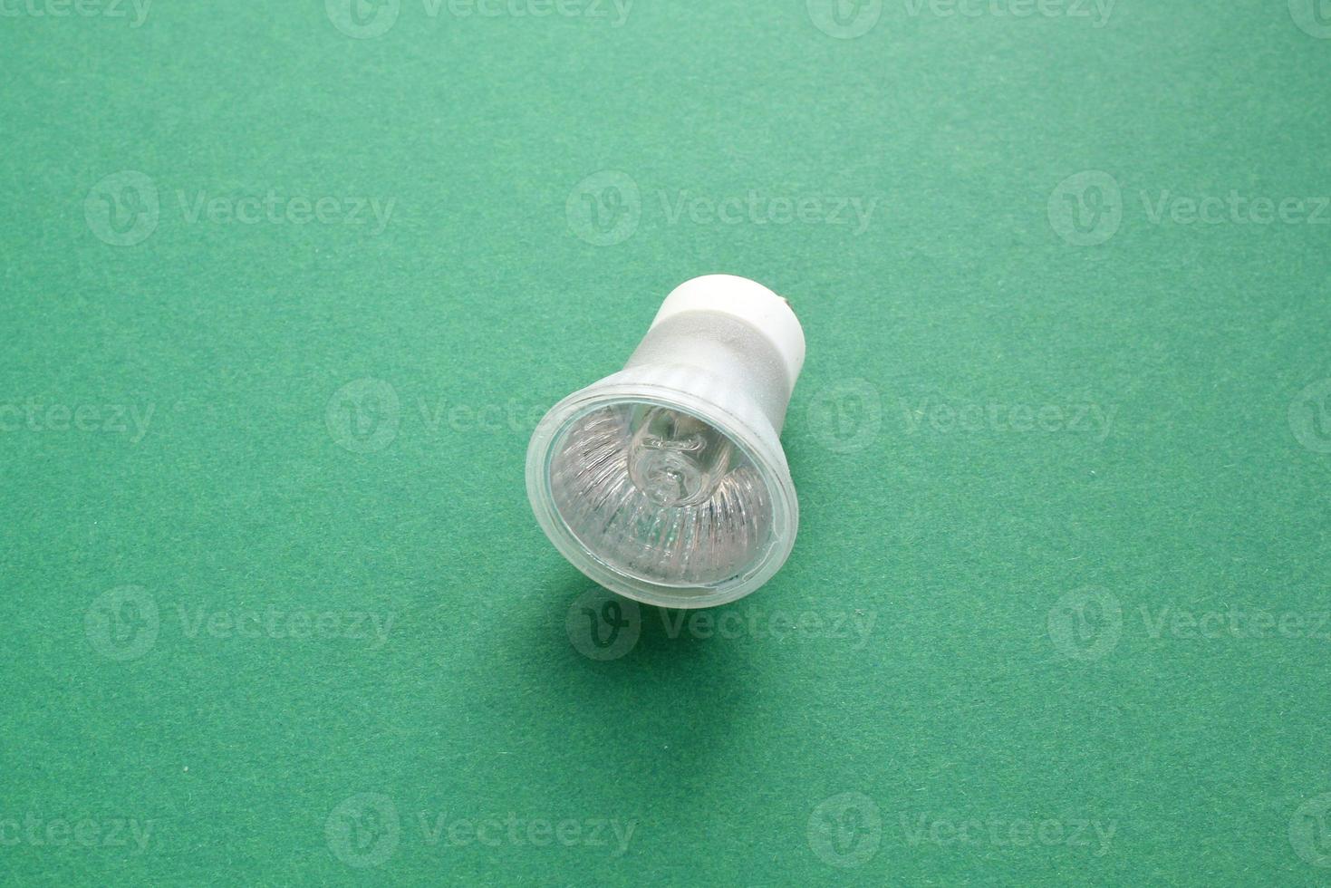 Electric LED light bulb lamp on green background with copy space. Eco saving power and environmental conservation energy efficiency concept. Ecological friendly and sustainable lifestyle. Flat lay photo