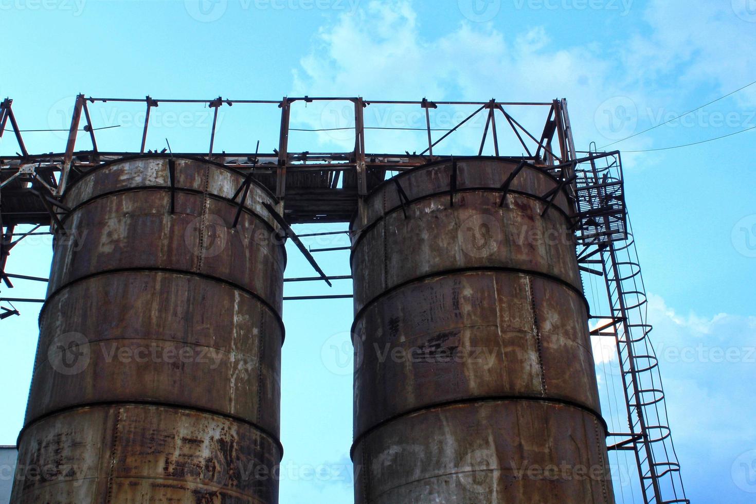 Rusty structures pipes of an old abandoned destroyed industrial steel factory. The overgrown ruins of complex building area. The concept of bankruptcy, and the closure of production and jobs photo