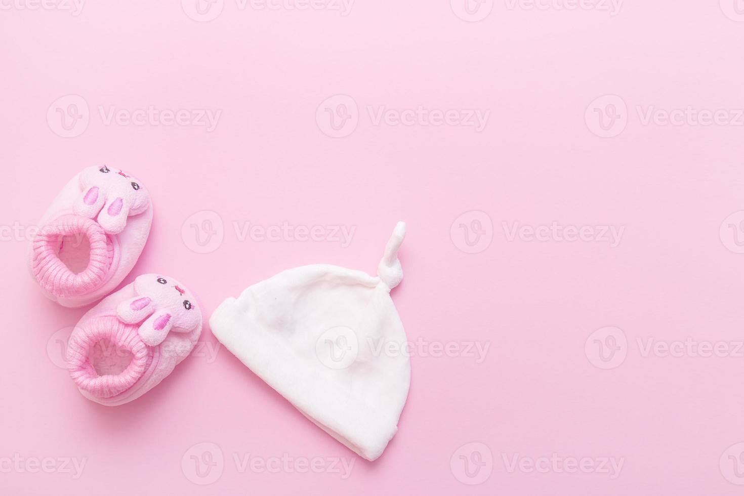 botines en forma de liebres y una gorra para un bebé sobre un fondo rosa con espacio para copiar foto