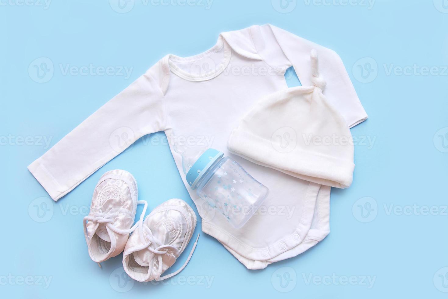 accessories for a newborn on a blue background - cap, bodysuit, booties, milk bottle photo