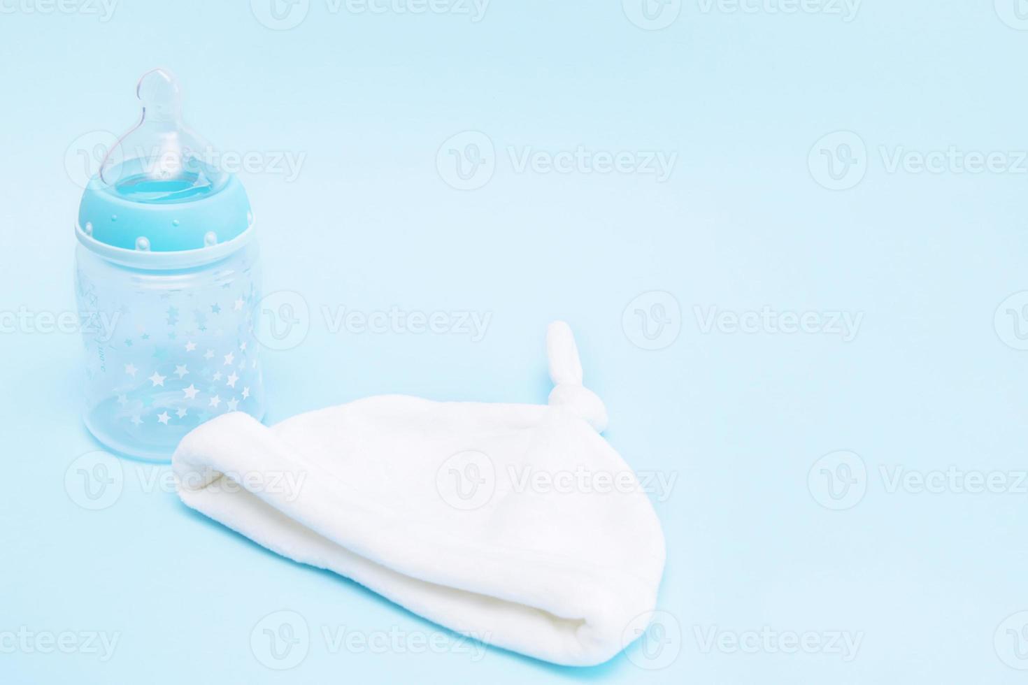 bottle with a pacifier and a cap for a baby on a blue background with