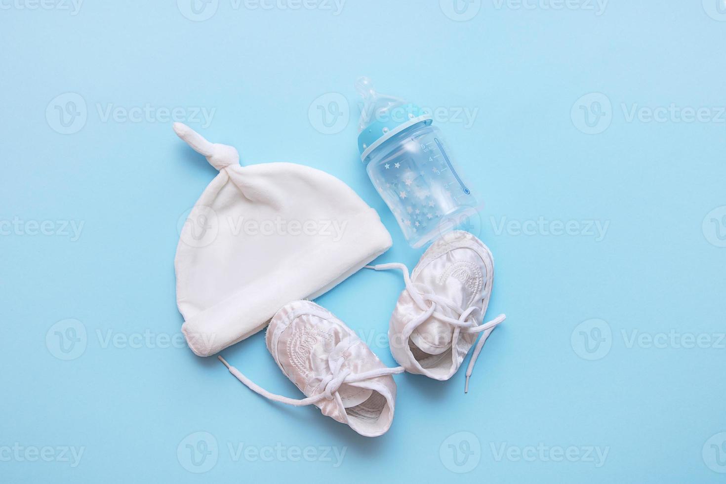 cap, booties and a bottle for the mixture on a blue background photo