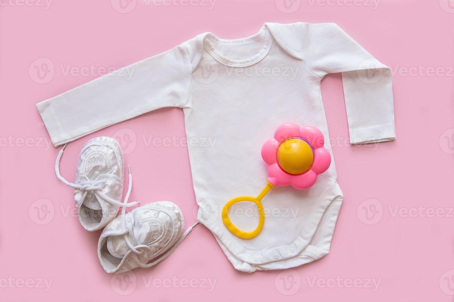 bodysuit for a newborn, rattle booties on a pink background, accessories for a newborn photo