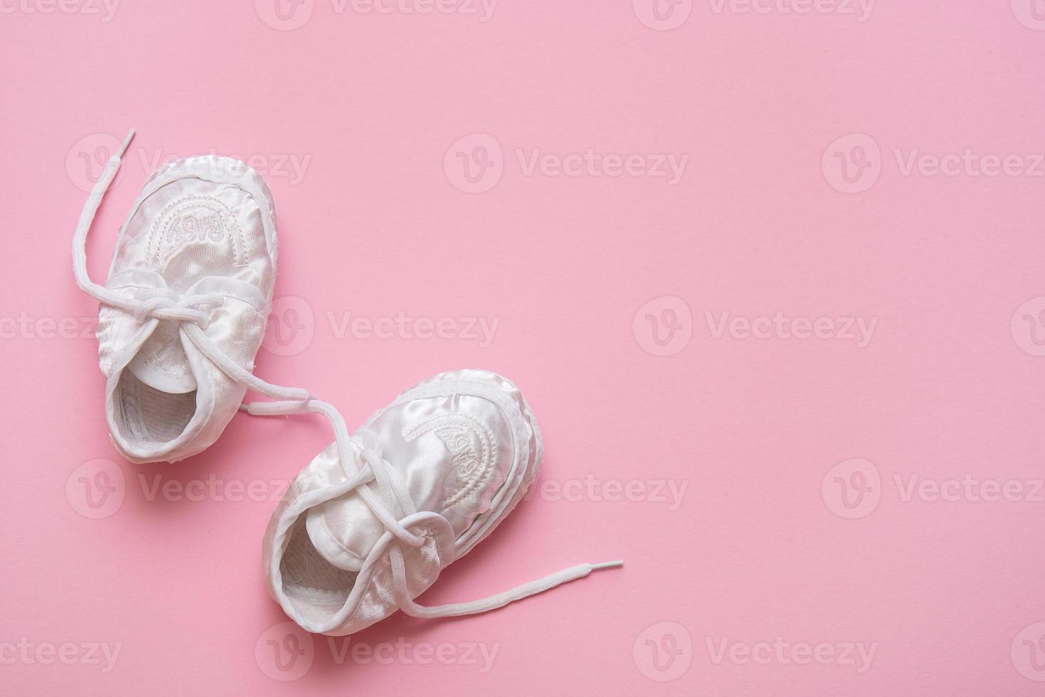 white booties with laces on a pink background with copy space photo