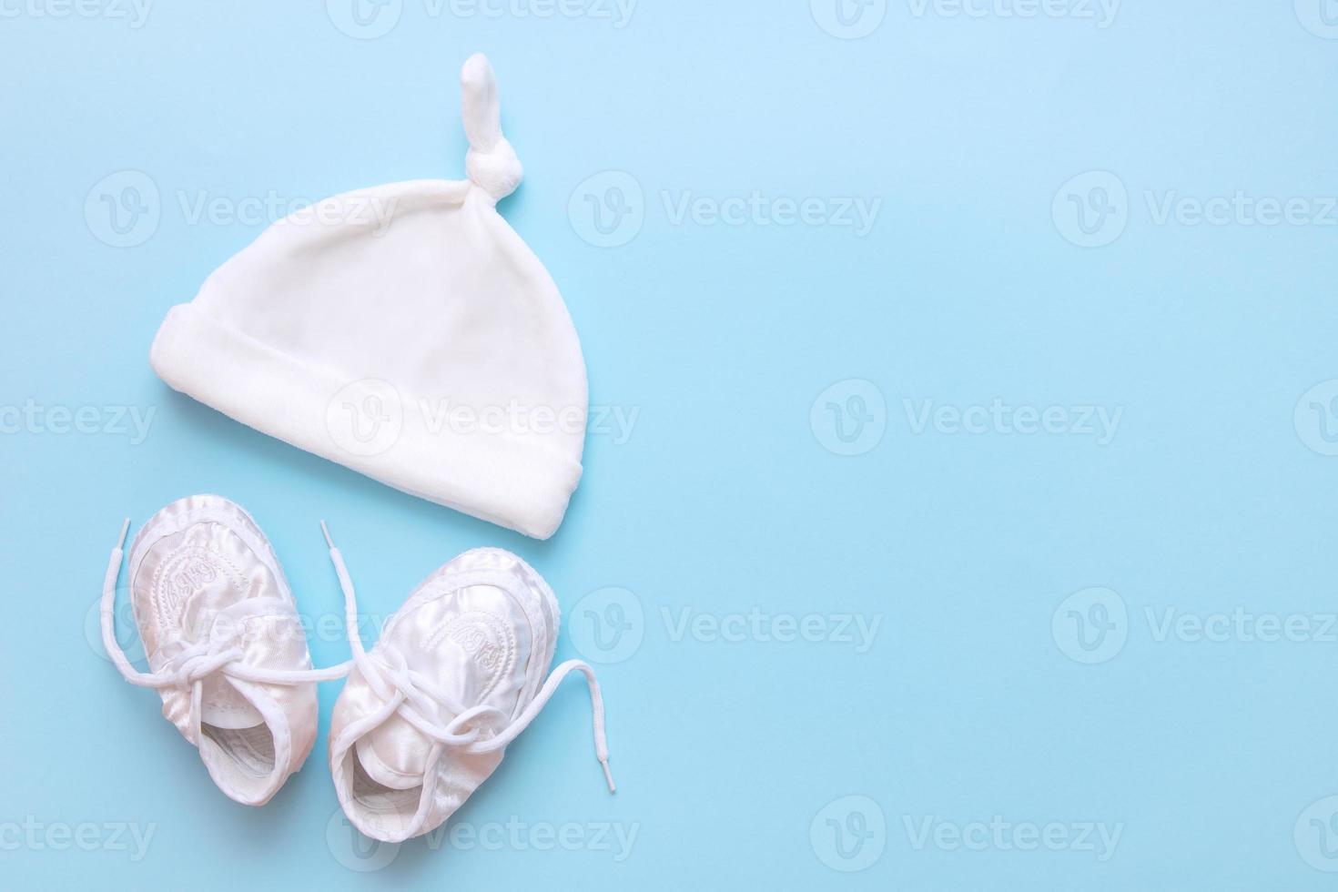 baby booties and cap on a blue background with copy space photo