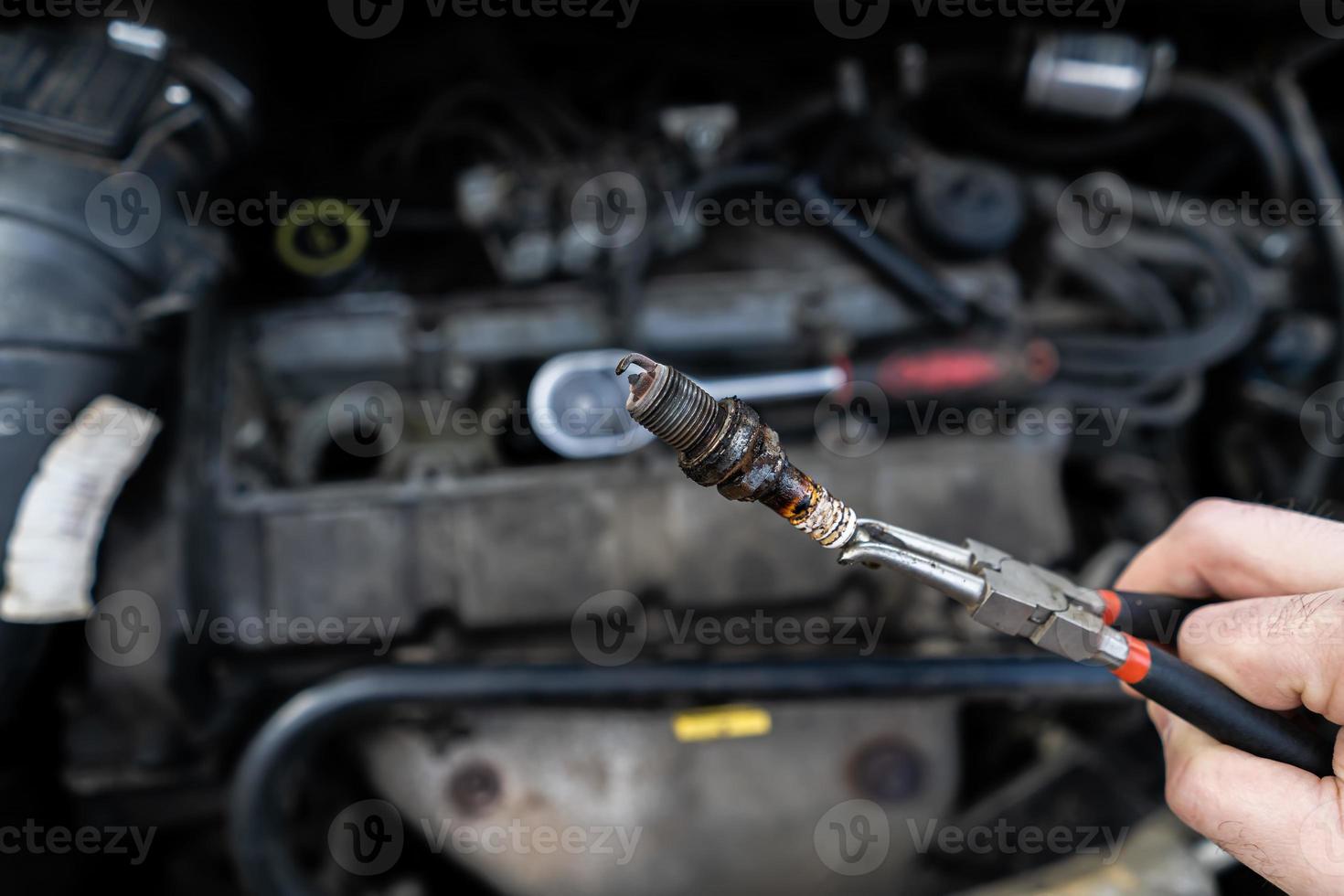 an old spark plug in the hands of a master against the background of the engine photo