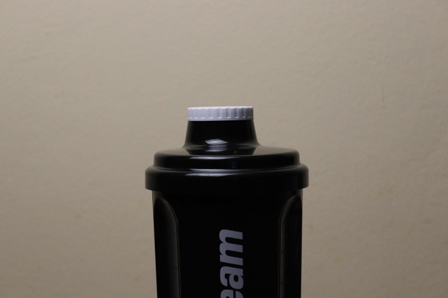 The top of a shaker that has a white cap and the colour of the container is black photo
