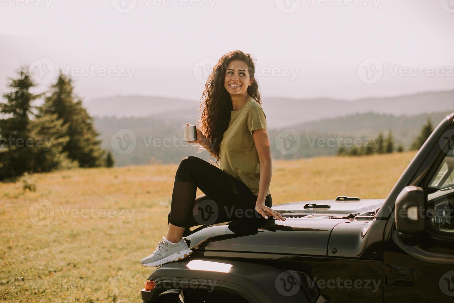 Young woman relaxing on a terrain vehicle hood at countryside photo