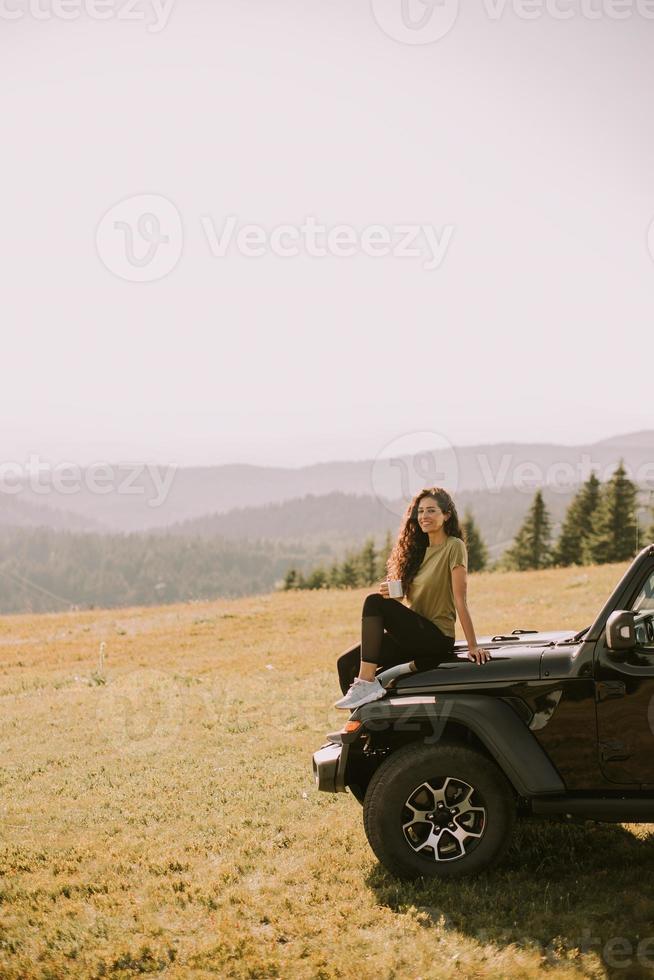 Young woman relaxing on a terrain vehicle hood at countryside photo