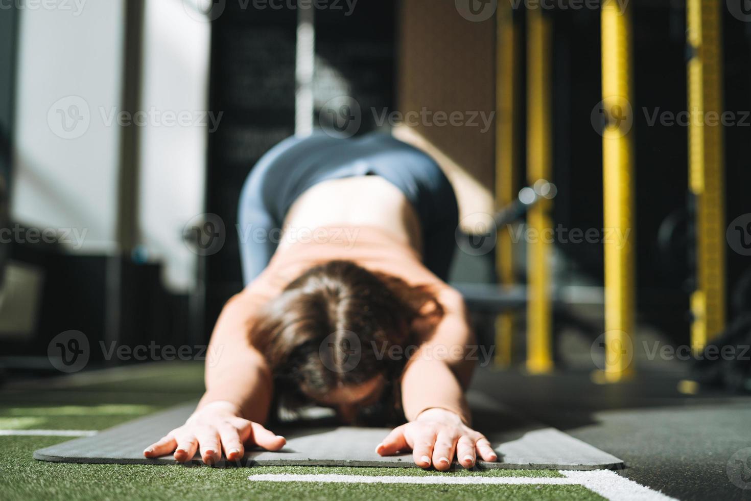 Young brunette woman doing stretching pilates, practice yoga on mat in fitness club, selective focus photo