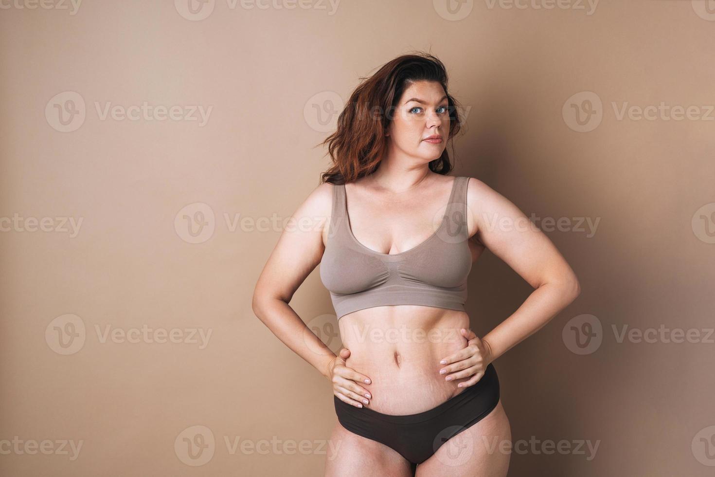 Portrait of self loving woman plus size in underwear on beige background, body love photo