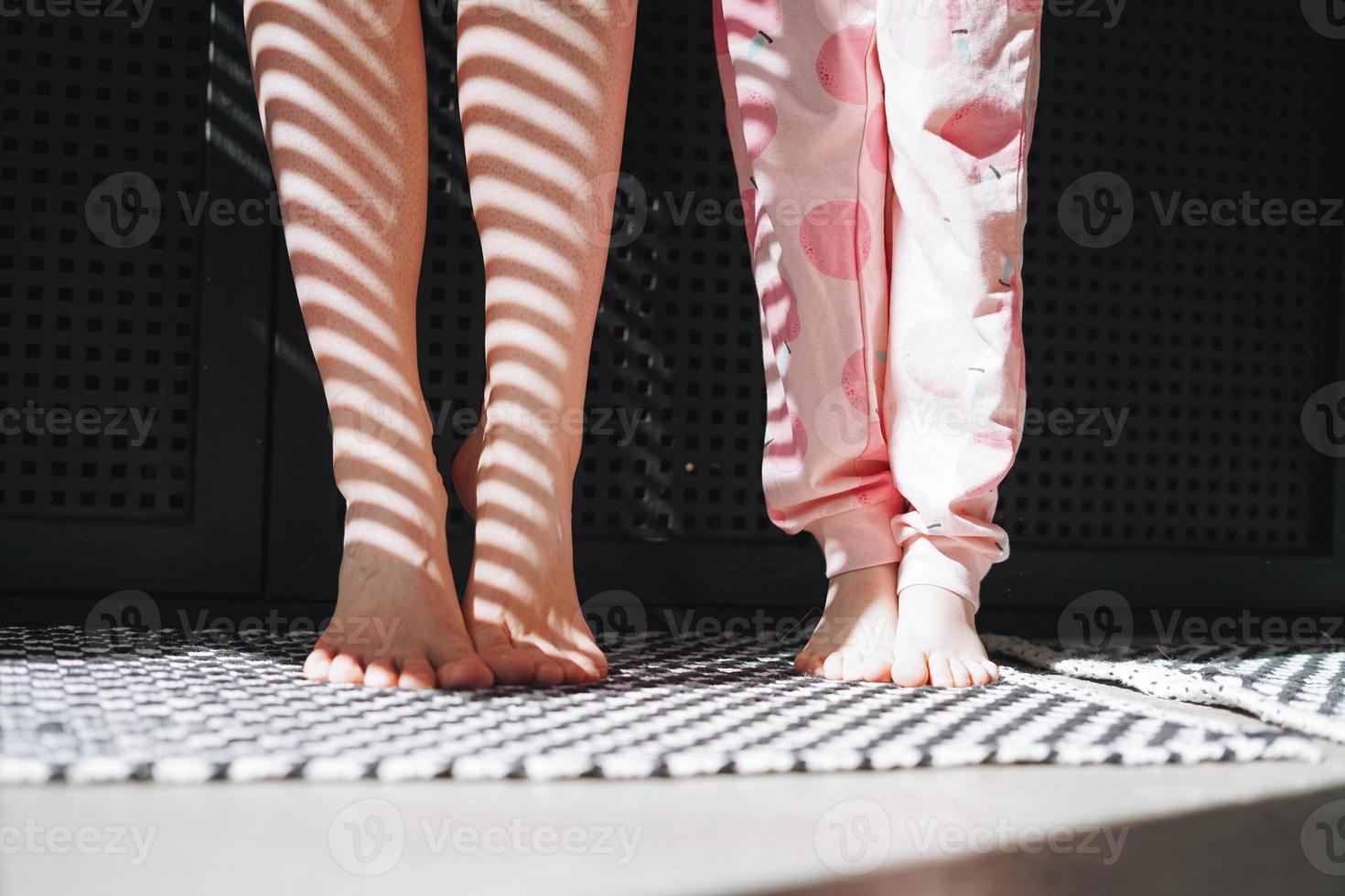 pies descalzos de mamá e hija en el baño de casa, luz y sombra foto