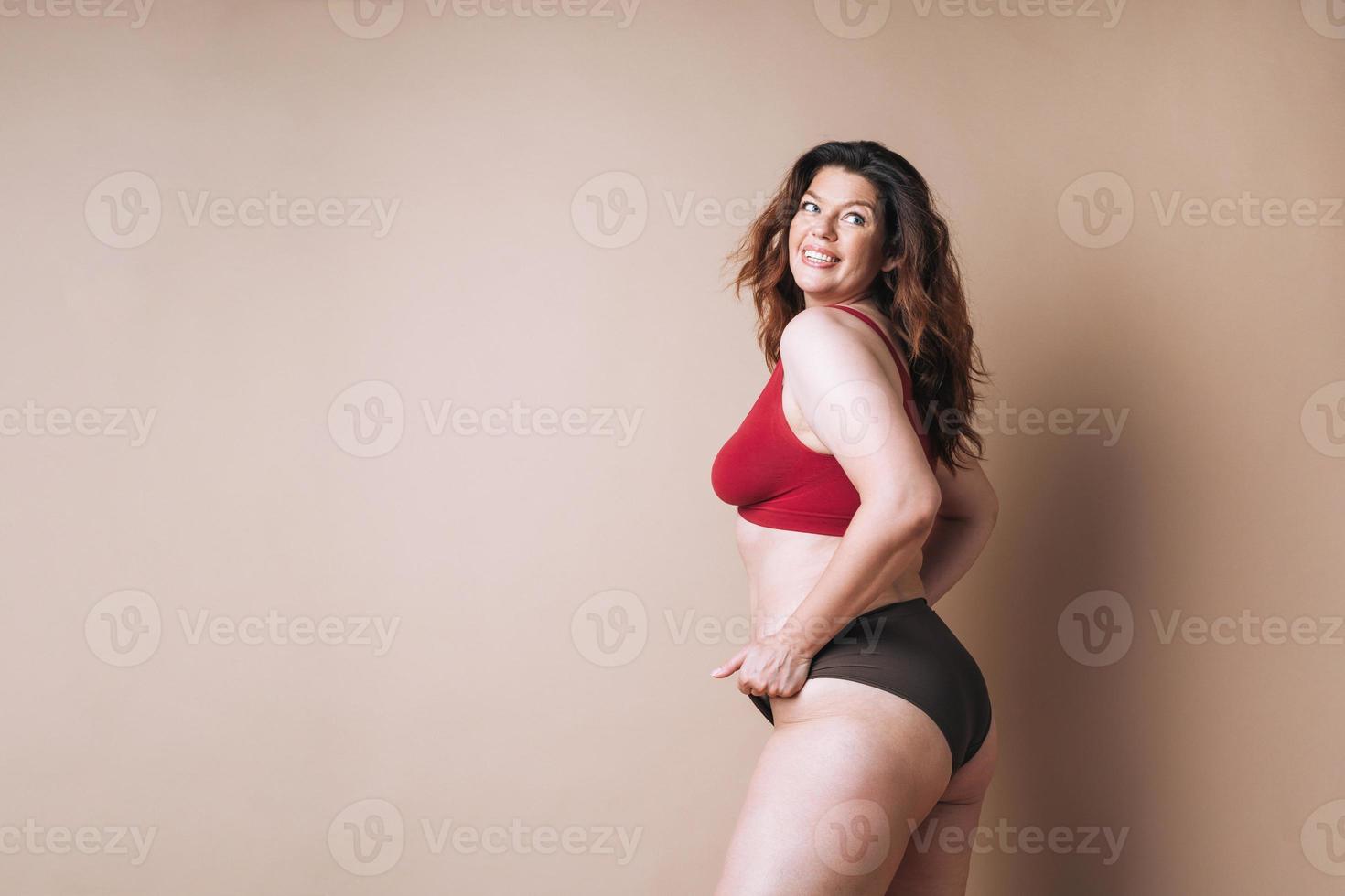 Portrait of self loving woman plus size in underwear on beige background, body love photo
