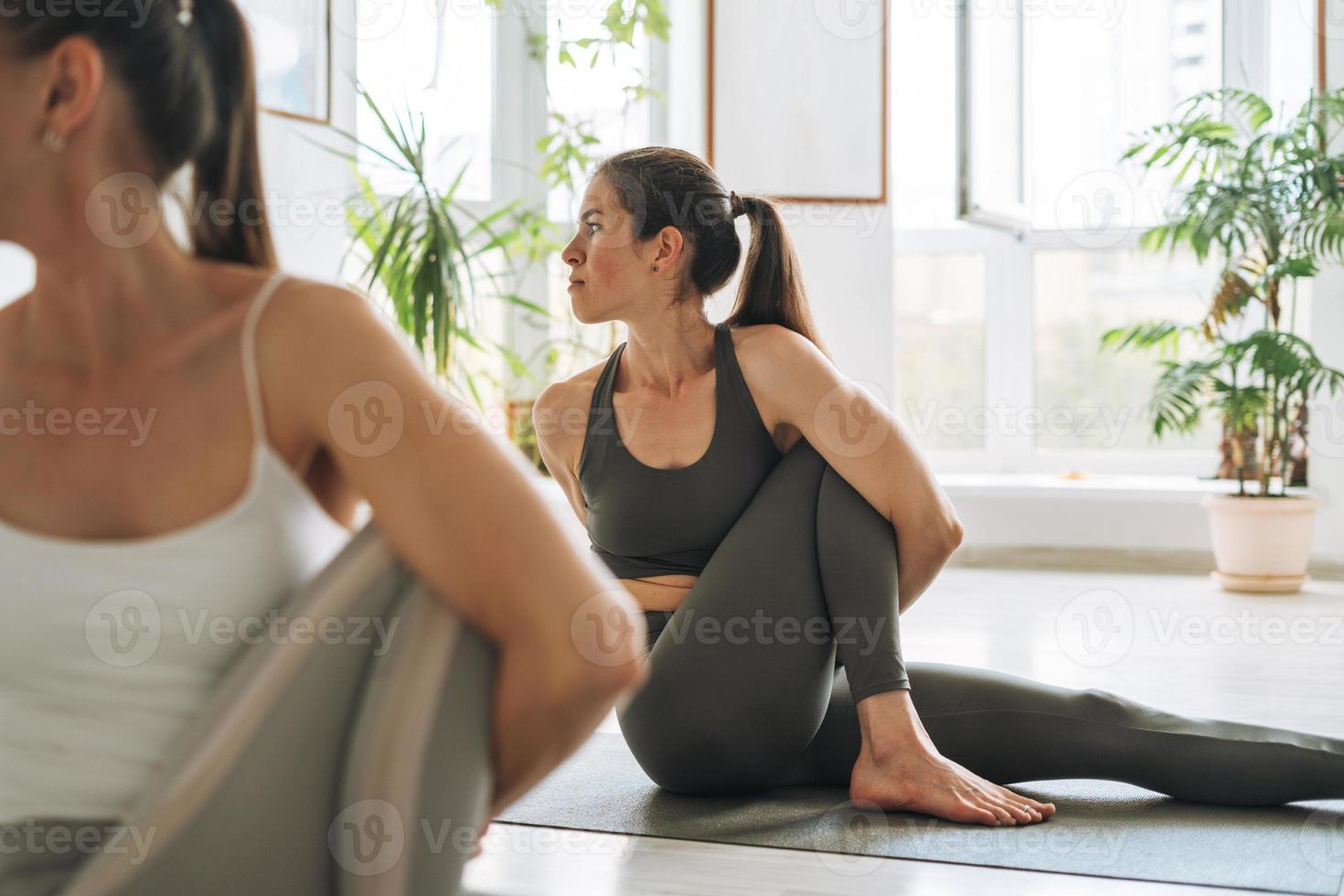 las mujeres jóvenes en forma practican yoga haciendo asanas en un brillante estudio de yoga. prácticas de ticher de yoga con estudiante en clase de yoga foto