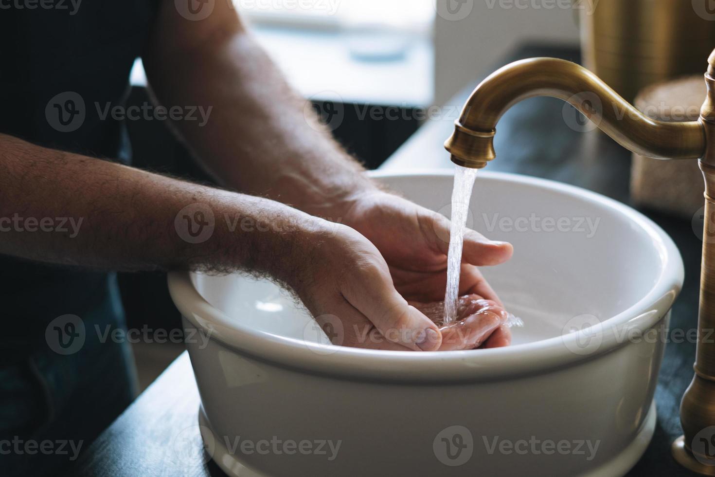 el joven se lava las manos en el lavabo del baño en casa foto
