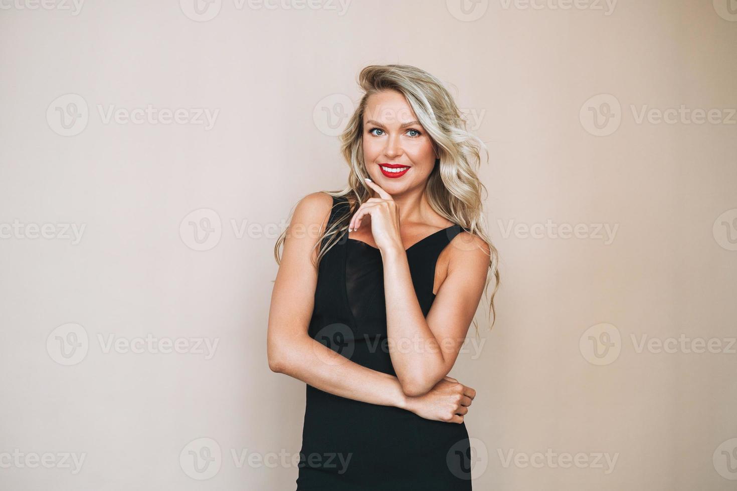 Portrait of gorgeous beautiful blonde young woman with bright makeup in evening dress on beige background photo