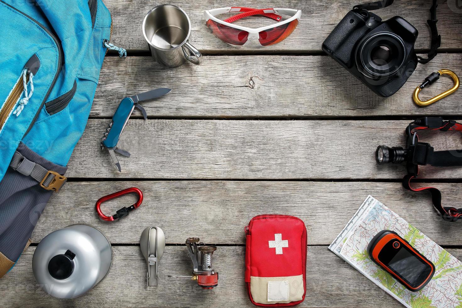 Top view of tourist equipment for travel and tourism on a rustic light wooden floor with an empty space in the middle. photo