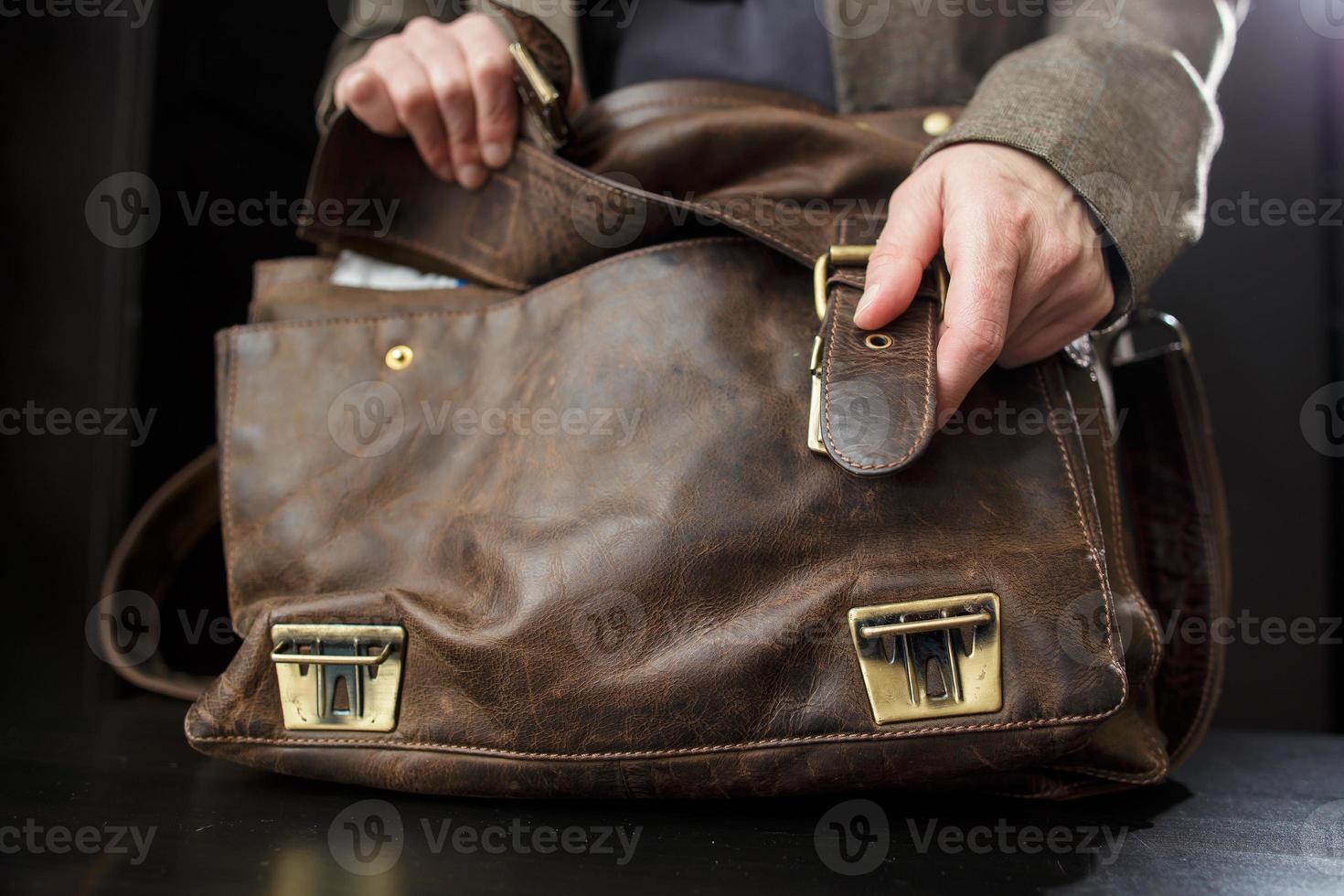 Hands professor open buckle on the old leather briefcase, before class. Education concept. photo