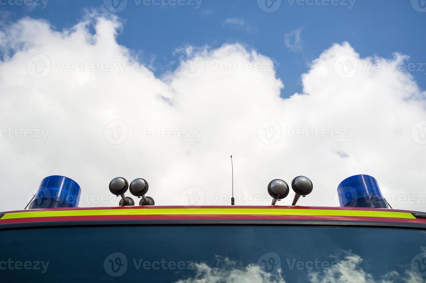 camión de bomberos con luces de señalización y sirena, contra el cielo azul y las nubes blancas. concepto de rescate y seguridad. copie el espacio foto