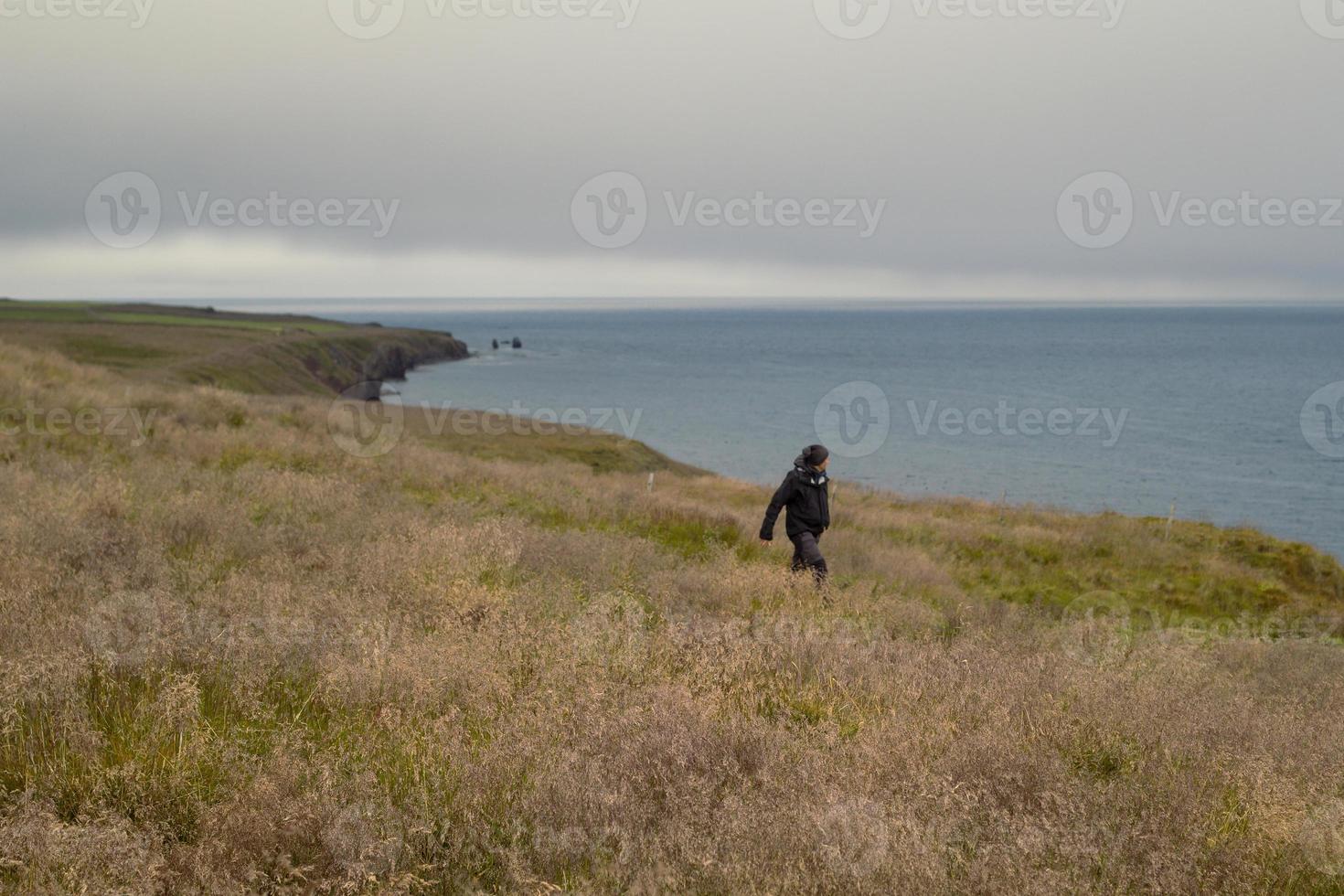 hombre caminando a lo largo de la foto del paisaje de la costa montañosa