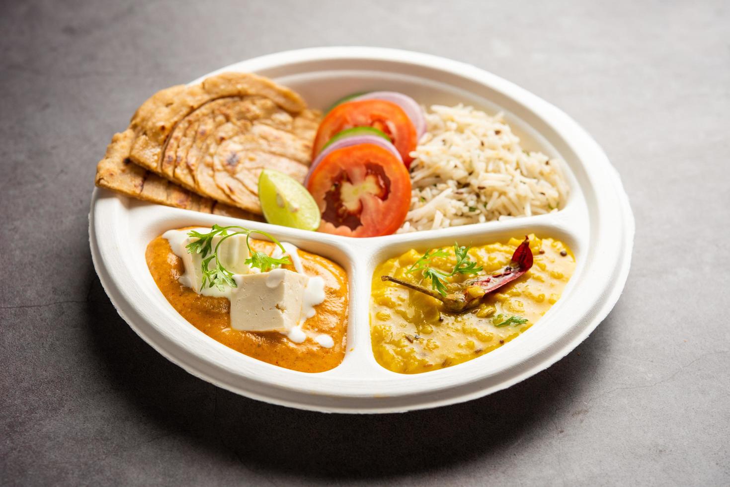 Mini comida del norte de la India, fuente de paquetes o combo thali con masala de mantequilla de paneer, roti, dal y arroz foto