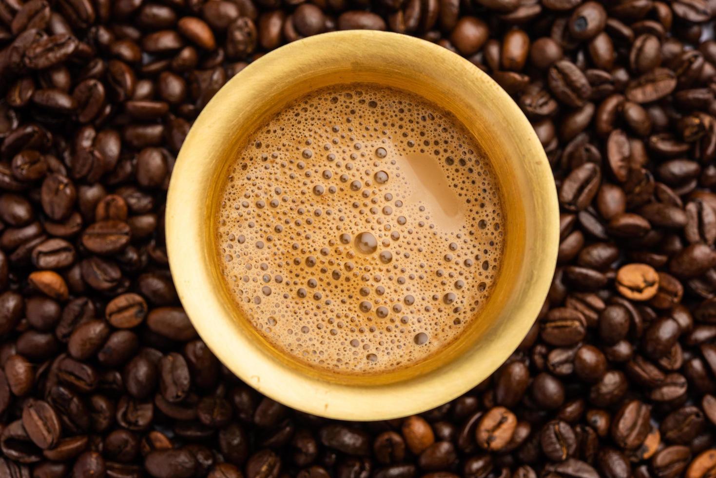 café de filtro del sur de la India servido en un vaso o taza tradicional sobre frijoles crudos tostados foto