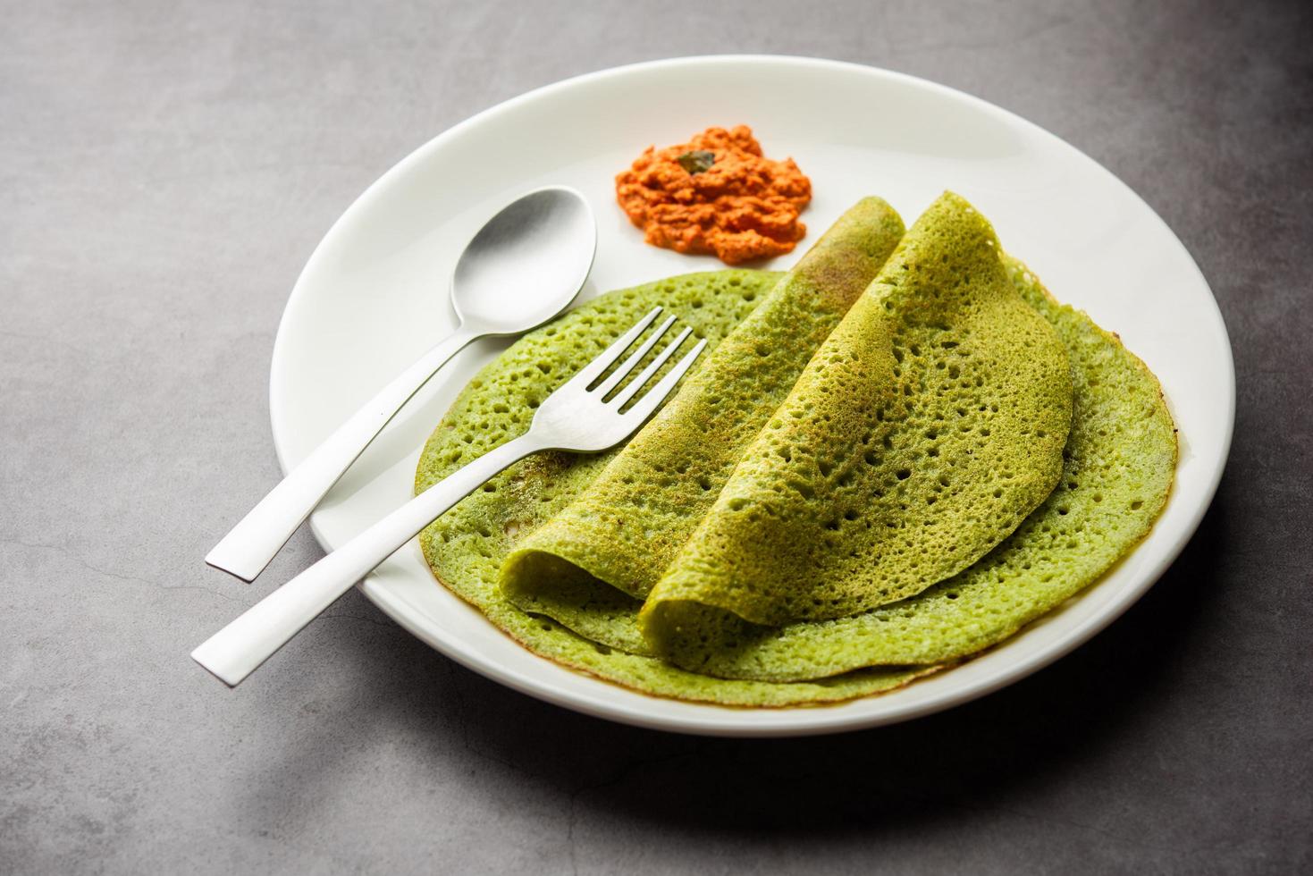 palak dosa hecho mezclando espinacas o keerai rebozados, servido con chutney rojo foto