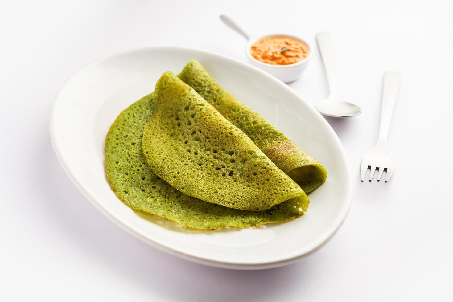 Palak dosa made using mixing spinach or keerai in batter, served with red chutney photo