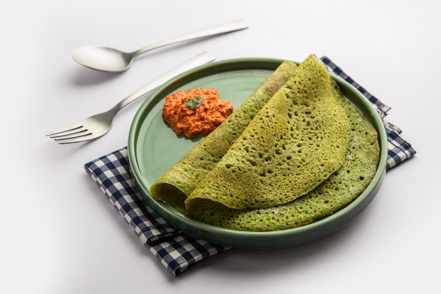 Palak dosa made using mixing spinach or keerai in batter, served with red chutney photo