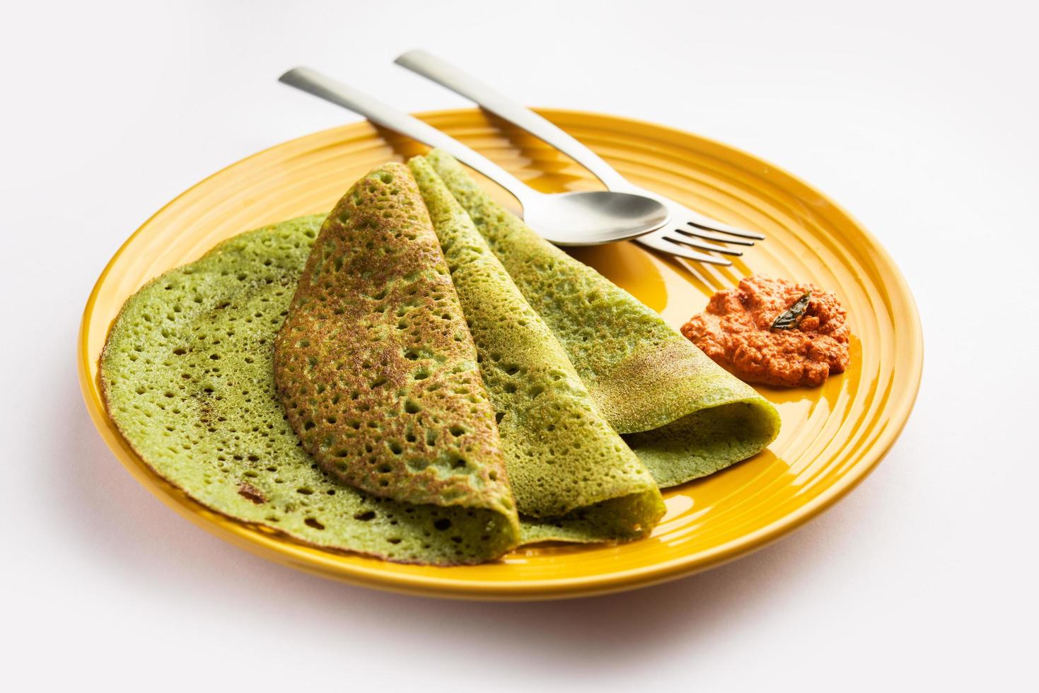 Palak dosa made using mixing spinach or keerai in batter, served with red chutney photo