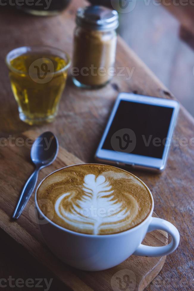 café bebida caliente capuchino arte con leche en una mesa vintage de madera, tiempo de café en un café de fondo de madera foto