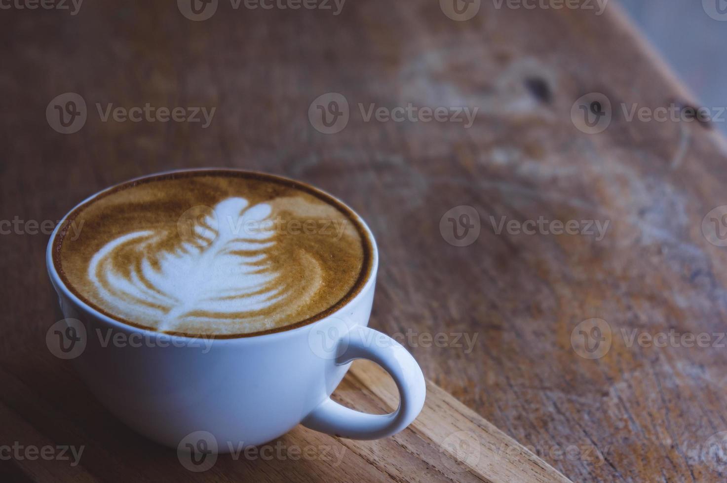 café bebida caliente capuchino arte con leche en una mesa vintage de madera, tiempo de café en un café de fondo de madera foto