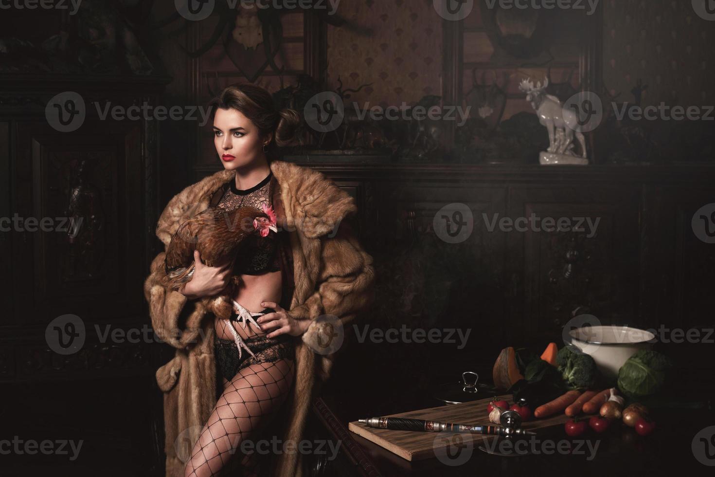 Gorgeous woman wearing fur coat is holding hen. Animal rights concept. photo