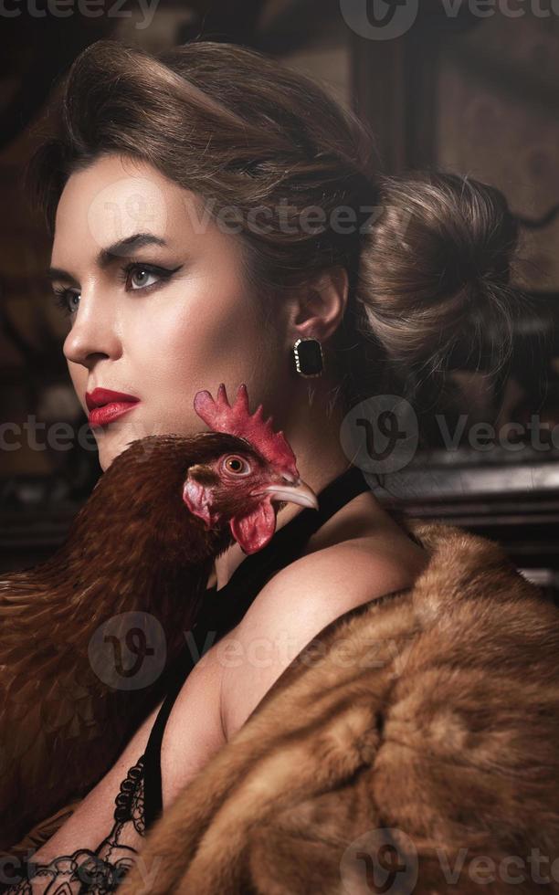 Gorgeous woman with beautiful makeup and hairstyle holding hen photo