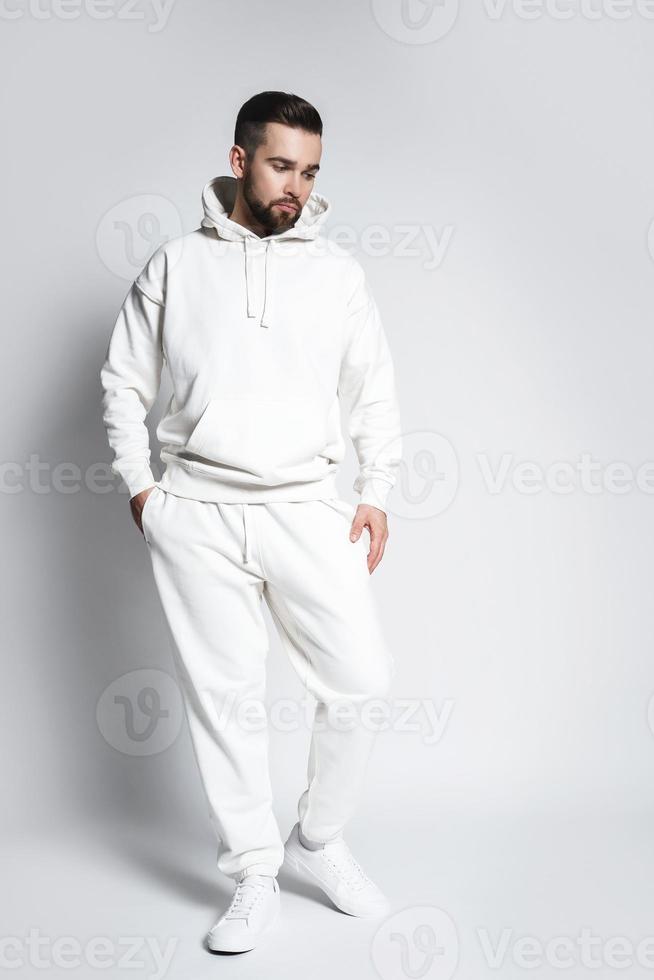 hombre guapo con capucha y pantalones blancos en blanco foto