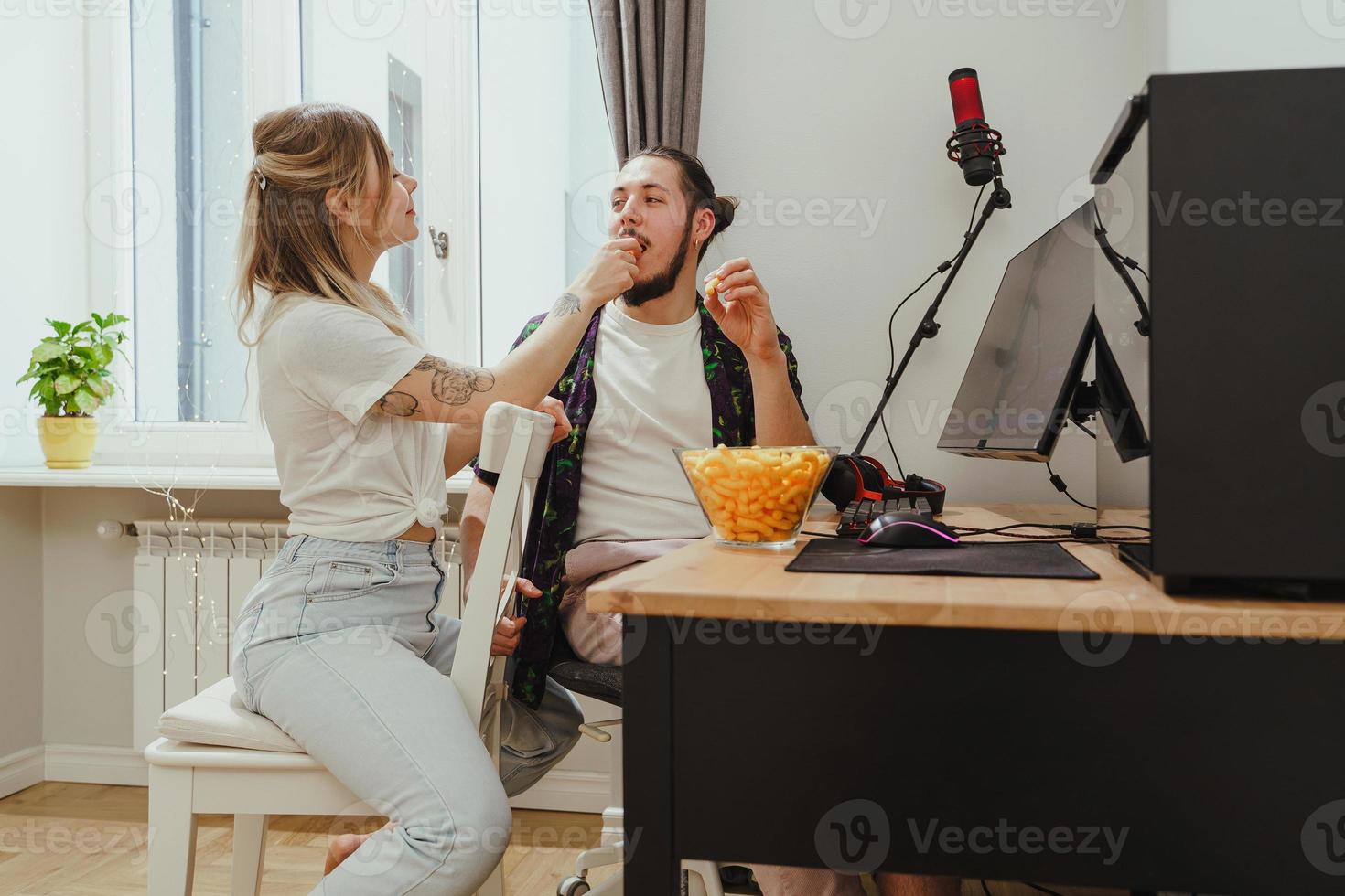 pareja comiendo bocadillos de queso mientras juega videojuegos o mira algo en línea en casa foto