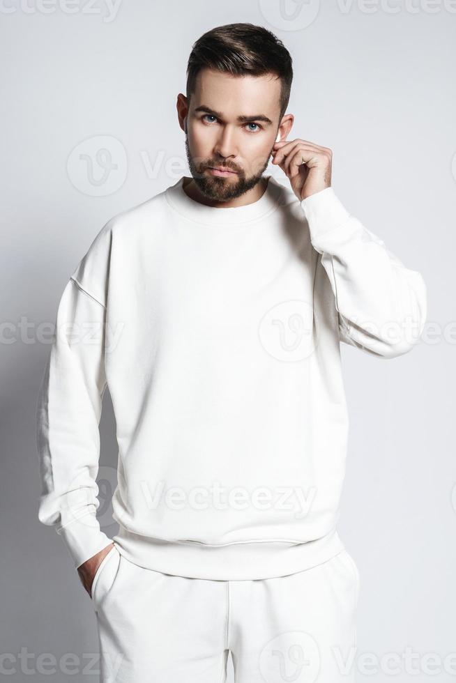 Handsome man wearing white sweatshirt with wireless earbuds photo