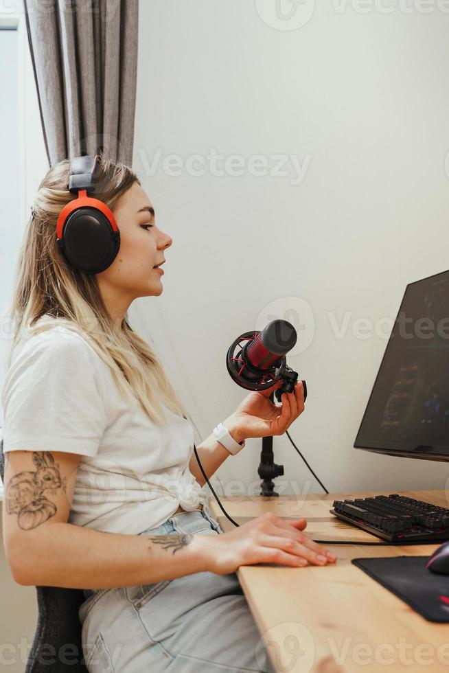 joven bloguera usando auriculares y micrófono de condensador durante un podcast en línea foto