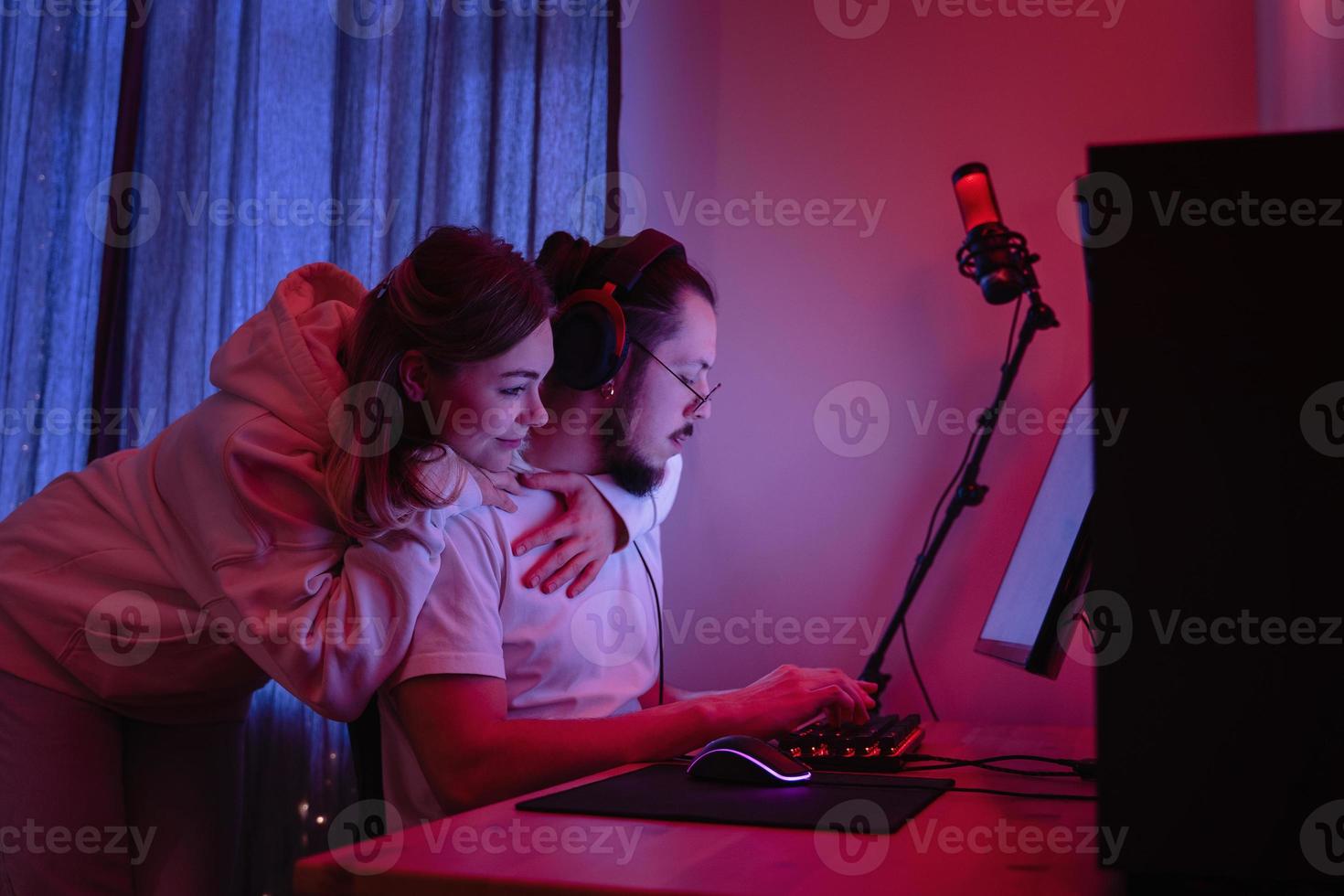 Young couple in room with neon light are using modern personal computer photo