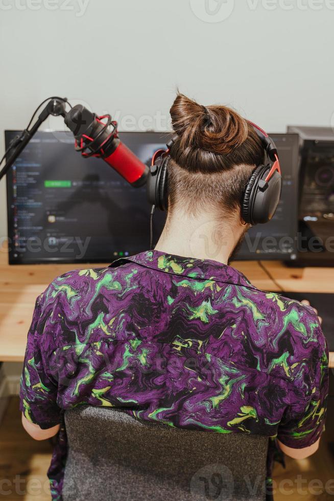 Young man blogger using headphones and condenser microphone  during online podcast stream photo