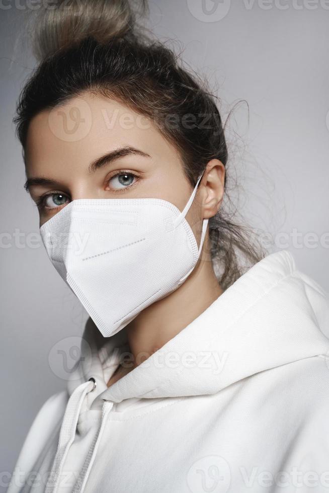 Young woman wearing white hoodie and ffp2 respirator mask photo