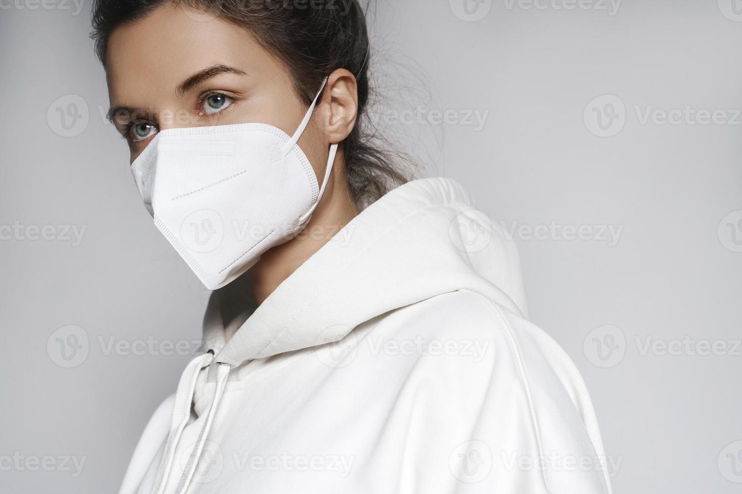 Young woman wearing white hoodie and ffp2 respirator mask photo