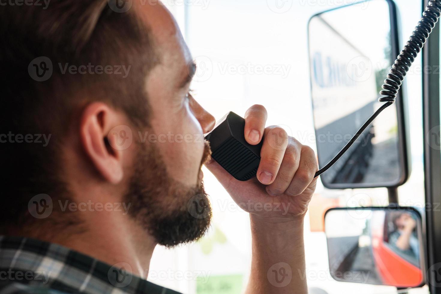 Truck driver talking by CB radio system in his vehicle photo