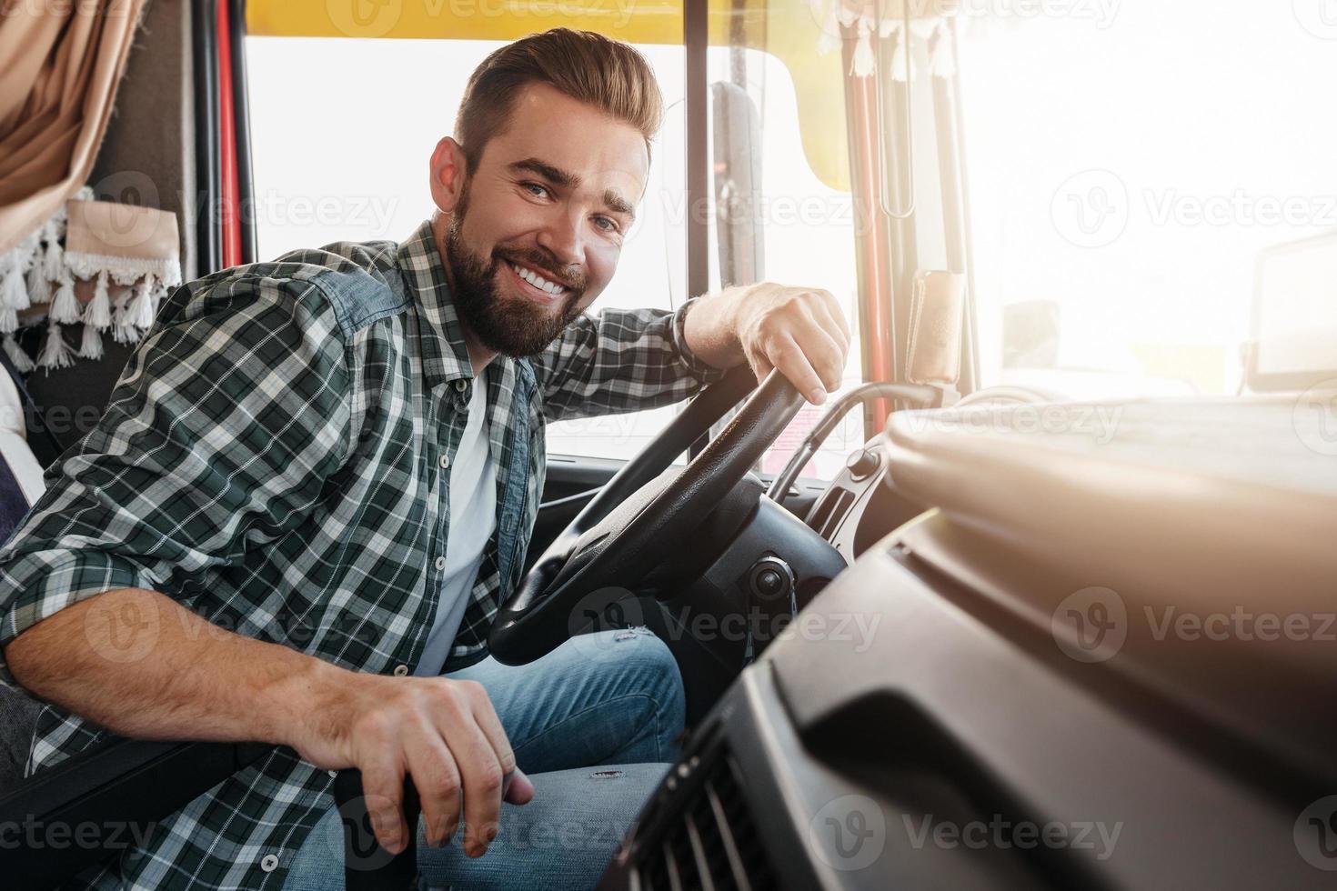 Young and happy smiling truck driver inside his vehicle photo