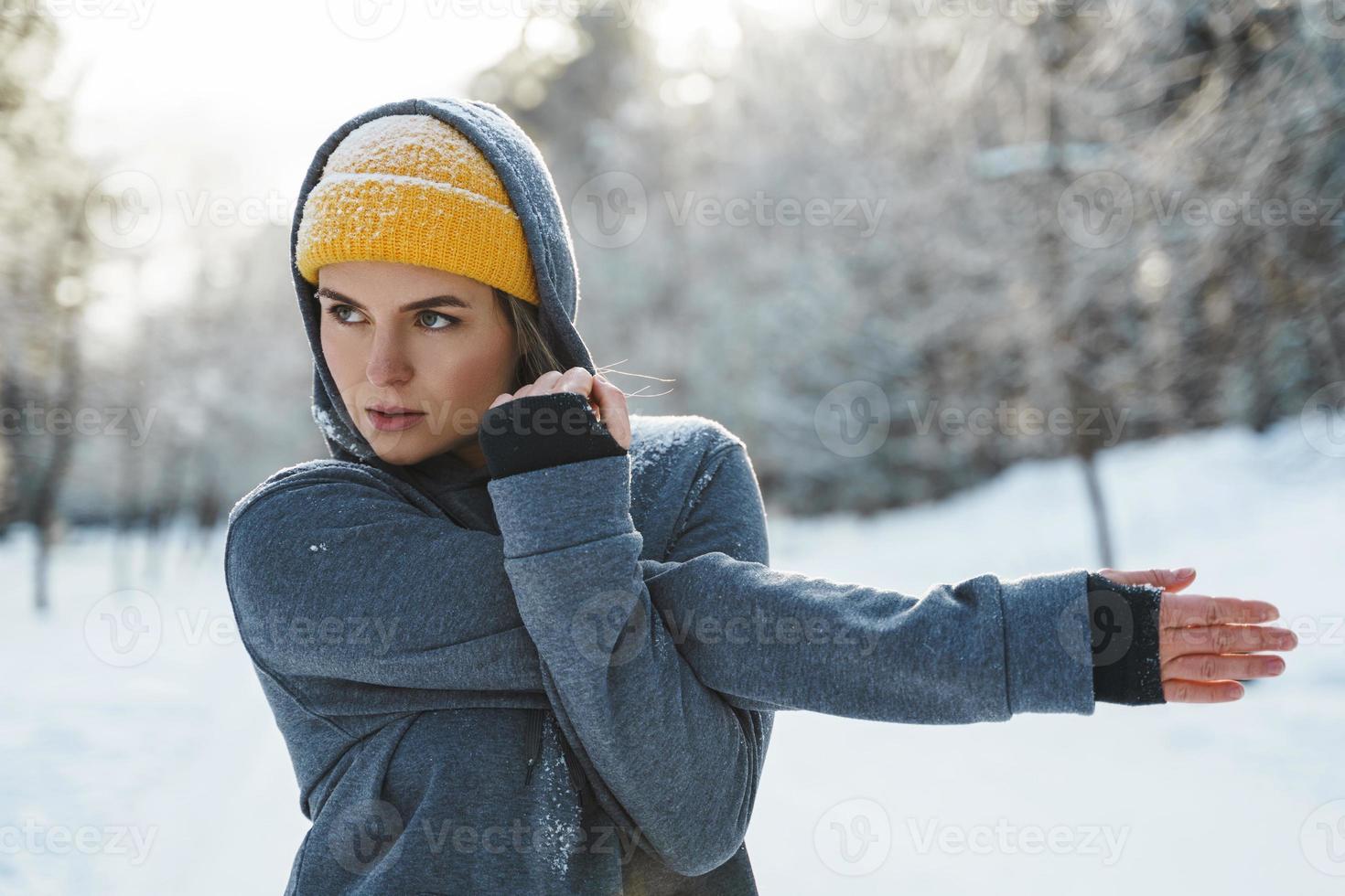 Young athletic woman warming up before her winter workout photo